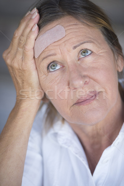 Woman in pain and band aid on forehead Stock photo © roboriginal