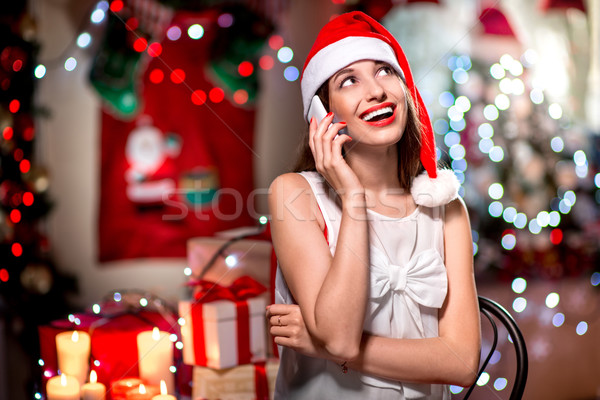 Fiatal nő mobiltelefon karácsony kalap beszél díszített Stock fotó © RossHelen