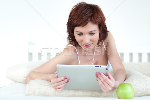 woman with an green apple and tablet at bed reading ebook   Stock photo © rozbyshaka