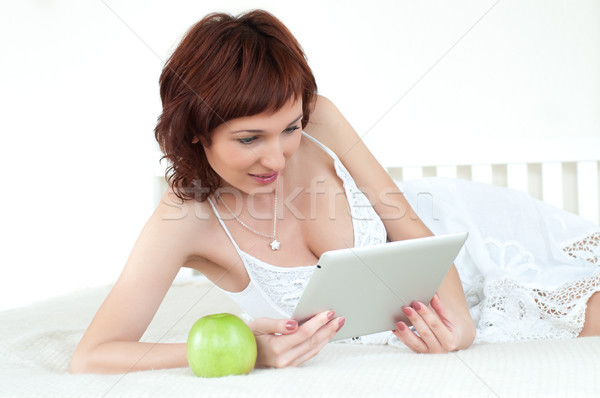 woman with an green apple and tablet at bed reading ebook   Stock photo © rozbyshaka