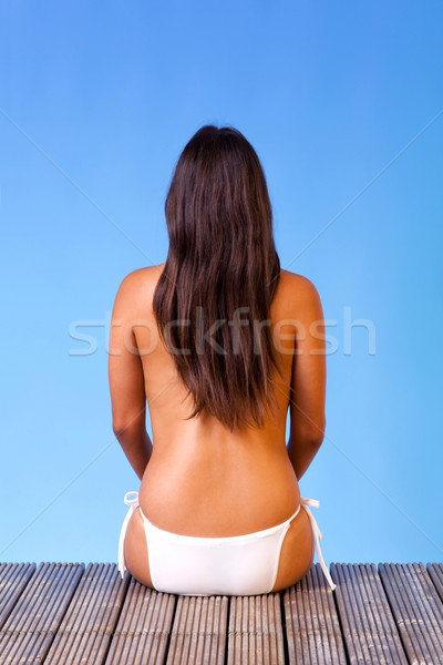 Topless woman in white bikini sat at the end of a pier Stock photo © RTimages