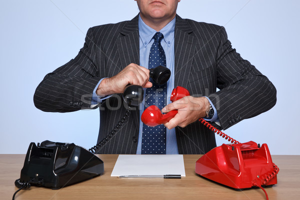 Businessman sat at desk with two telephones. Stock photo © RTimages