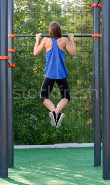 Stock photo: Young athletic girl pulls on the bar.