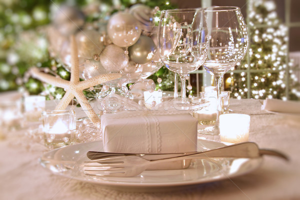 Stock photo: Elegantly lit  holiday dinner table with white ribboned gift