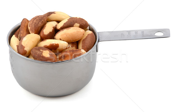 Stock photo: Whole brazil nuts in a metal cup measure