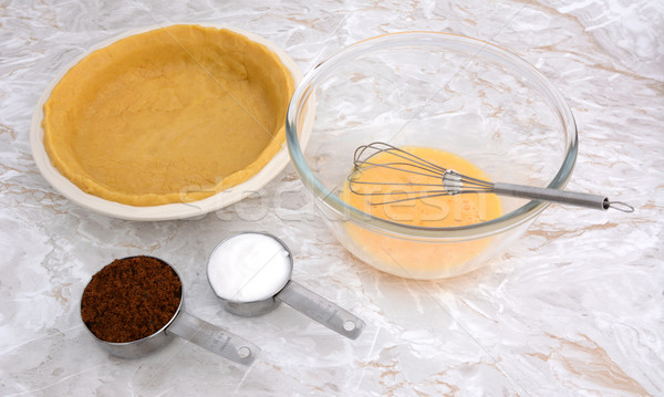 Stock photo: Lined pie dish, beaten egg and measuring cups of sugar