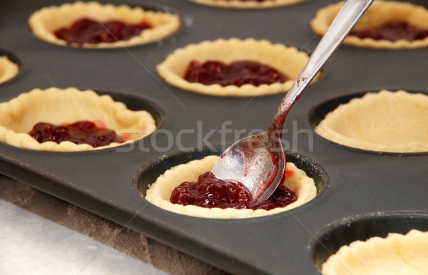 Closeup of jam tarts being filled with a teaspoon Stock photo © sarahdoow