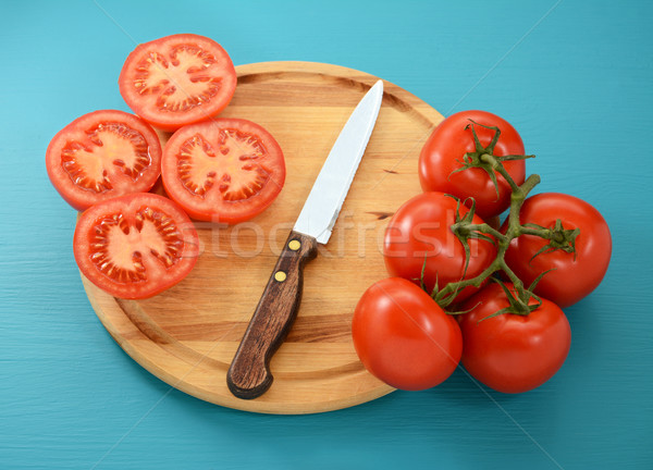 Tomatoes, whole and sliced with knife on wooden board Stock photo © sarahdoow