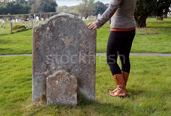 Stock photo: Woman rests her hand thoughtfully on a headstone