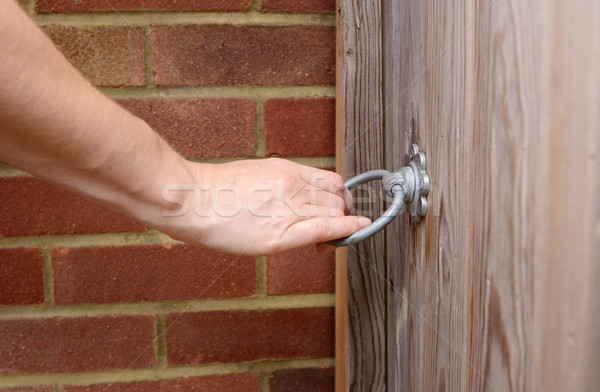 Woman turns a metal ring handle to open a gate Stock photo © sarahdoow