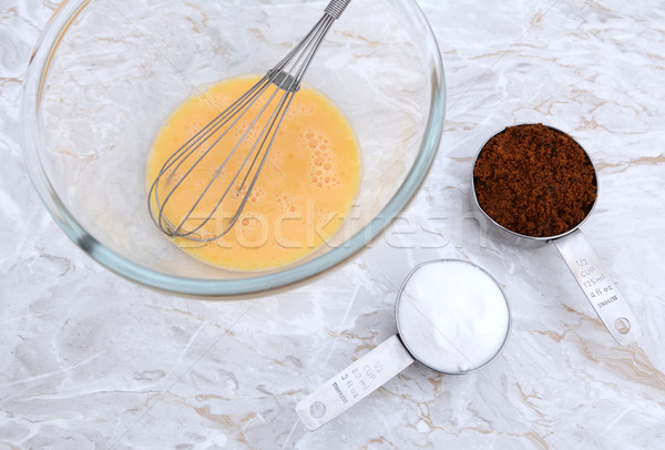 Stock photo: Beaten egg with whisk and measuring cups of sugar