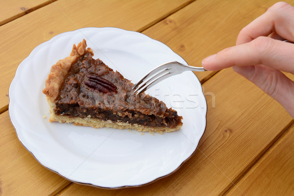 Woman uses dessert fork to cut into a slice of pecan pie Stock photo © sarahdoow