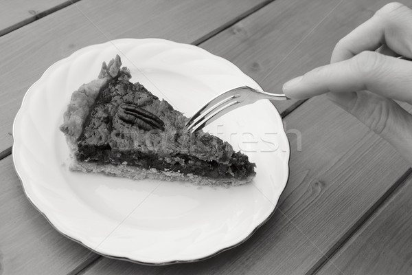 Woman uses dessert fork to cut into a slice of pecan pie Stock photo © sarahdoow