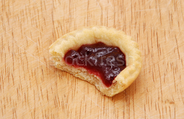 One jam tart with a bite taken, on a wooden table Stock photo © sarahdoow