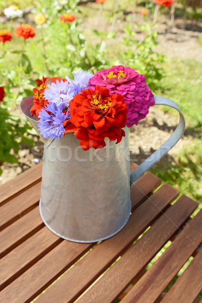 Pitcher filled with fresh flowers on a garden table Stock photo © sarahdoow