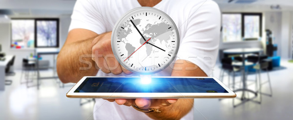 Businessman holding a clock over his digital tablet Stock photo © sdecoret