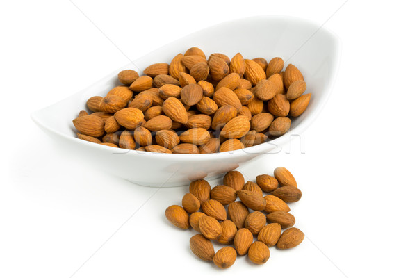 Cracked and shelled almond kernels in white bowl Stock photo © ShawnHempel