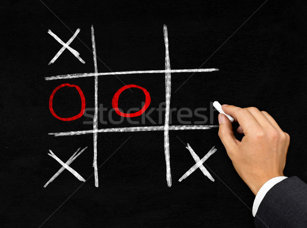 Tic-Tac-Toe game on blackboard by businessman Stock photo © ShawnHempel