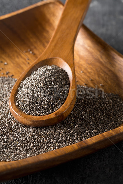 Raw unprocessed black chia seeds on wooden spoon on chia seeds Stock photo © ShawnHempel