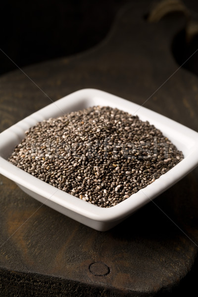 Raw unprocessed black chia seeds in small white bowl on wooden b Stock photo © ShawnHempel