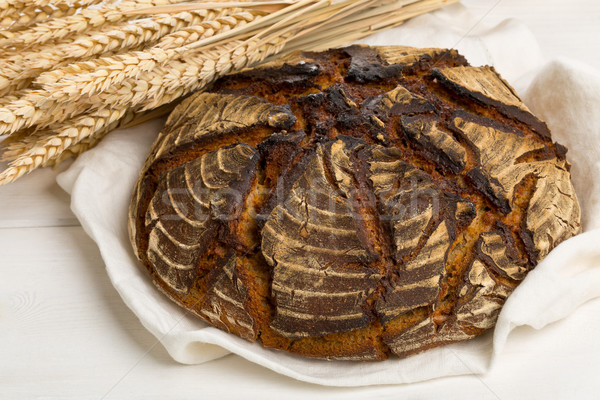 Hand made bread loaf with wheat ears on white wood Stock photo © ShawnHempel