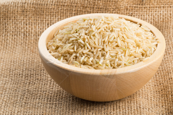 Natural brown uncooked rice in wooden bowl on burlap Stock photo © ShawnHempel