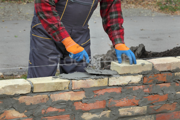 Stock photo: Worker building brick wall using trowel