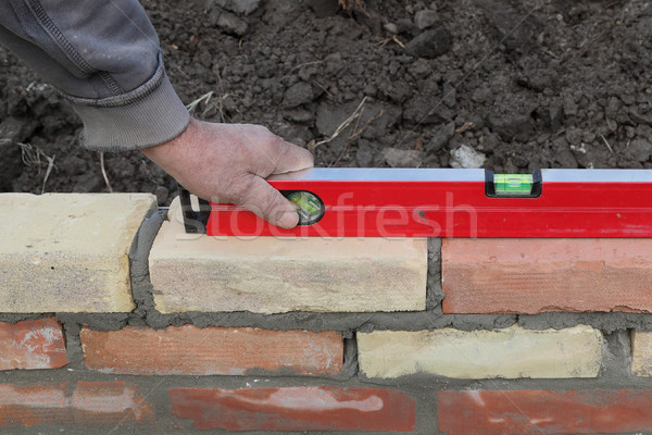 Worker building brick wall, control with level tool Stock photo © simazoran