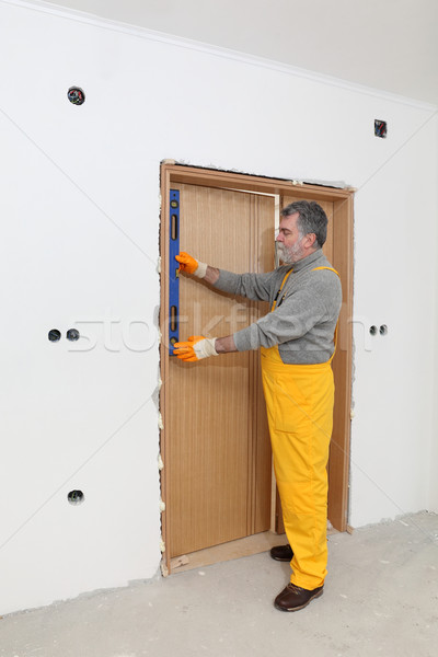 Stock photo: Builder measure verticality of door with level tool