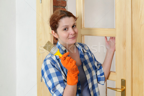 Young girl worker, painting new wooden door Stock photo © simazoran