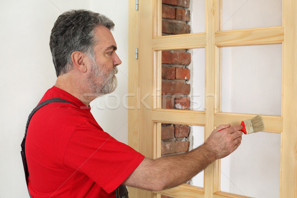 Home renovation, worker painting wooden door, varnishing Stock photo © simazoran