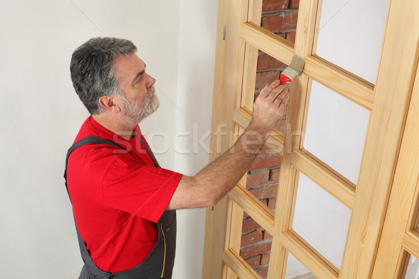 Home renovation, worker painting wooden door, varnishing Stock photo © simazoran