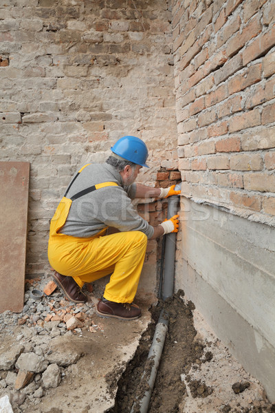 Plumber at construction site installing sewerage tube Stock photo © simazoran