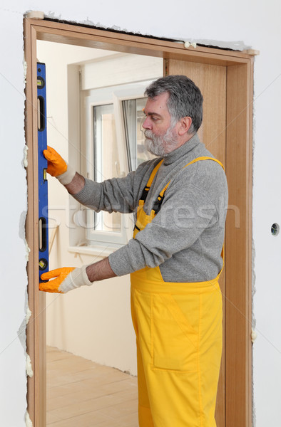 Stock photo: Builder measure verticality of door with level tool