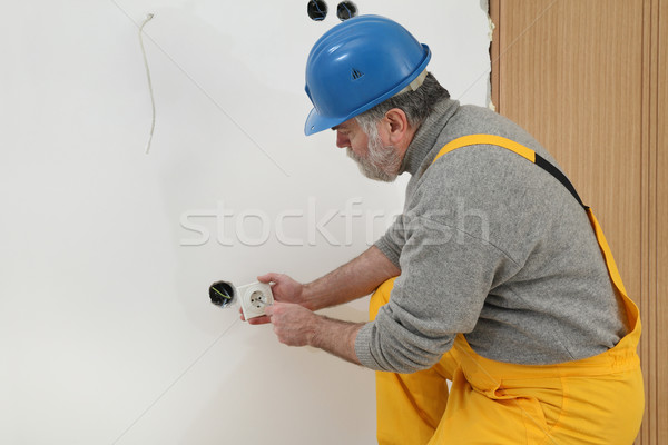 Stock photo: Electrician at construction site install electrical plug
