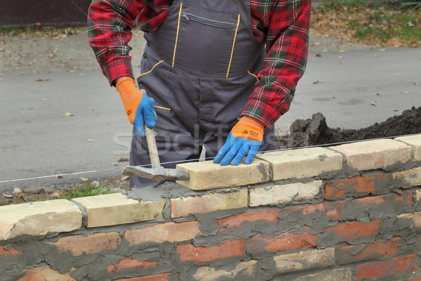 Stock photo: Worker building brick wall using hammer