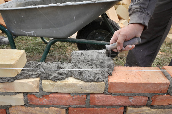 Worker building brick wall using trowel Stock photo © simazoran