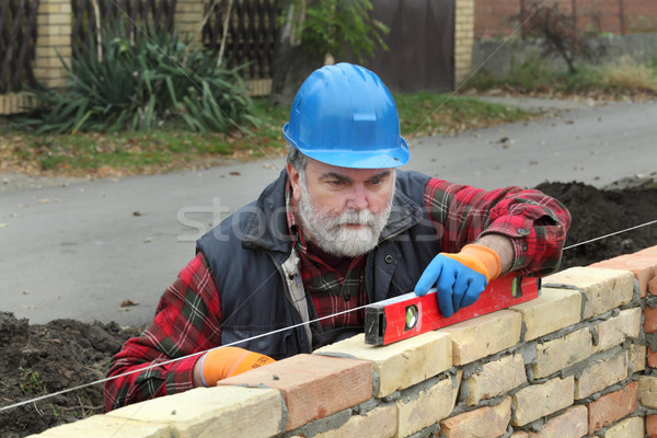 Worker examining brick wall using level tool Stock photo © simazoran