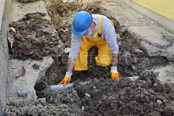 Plumber at construction site repair sewerage tube Stock photo © simazoran