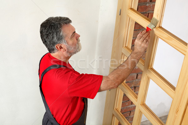 Home renovation, worker painting wooden door, varnishing  Stock photo © simazoran