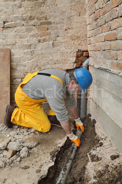Plumber at construction site installing sewerage tube Stock photo © simazoran