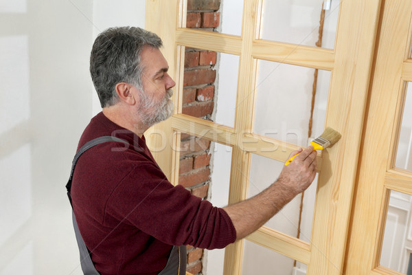 Home renovation, worker painting wooden door, varnishing Stock photo © simazoran