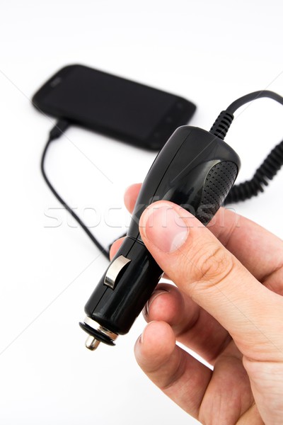 Hand holding car charger. Cell phone in background Stock photo © simpson33