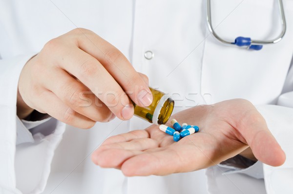 Doctor pouring pills on his hand. Medical concept in hospital. Stock photo © simpson33