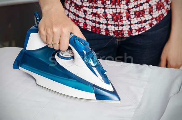 Woman irons clothes on ironing board with steaming iron Stock photo © simpson33