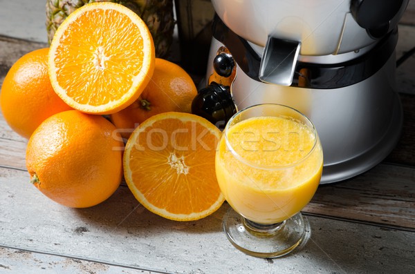Stock photo: Juicer and orange juice in glass on wooden desk