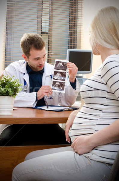 Stock photo: Doctor showing baby ultrasound image to pregnant woman