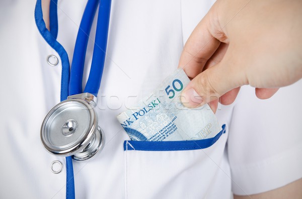 Patient bribing doctor, puts money into the pockets Stock photo © simpson33