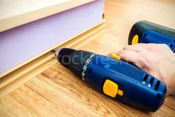 Hand holding drill. Worker lying floor panels. Stock photo © simpson33