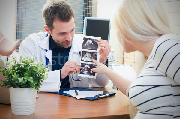 Stock photo: Doctor showing baby ultrasound image to pregnant woman
